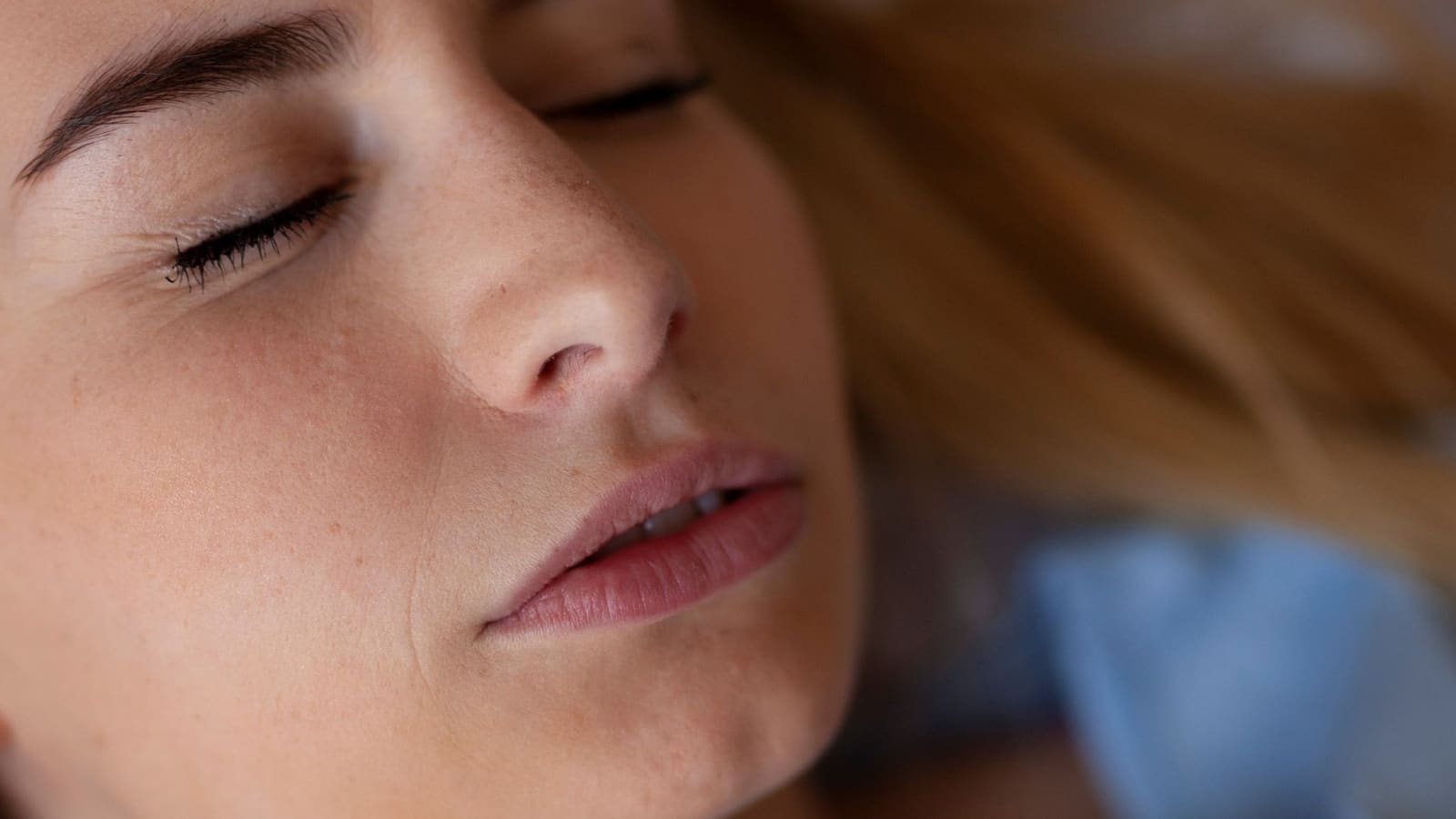 Primer plano de una mujer dormida con la mandíbula tensa y los labios apretados