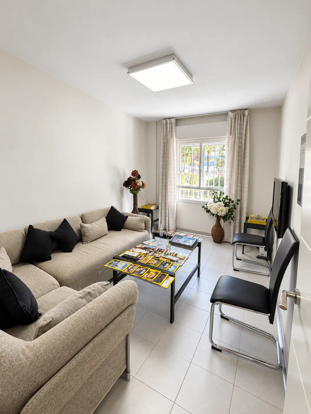 Sala de espera de Clínica Dental Arosa en Peñagrande, con sofá, revistas y luz natural de la ventana