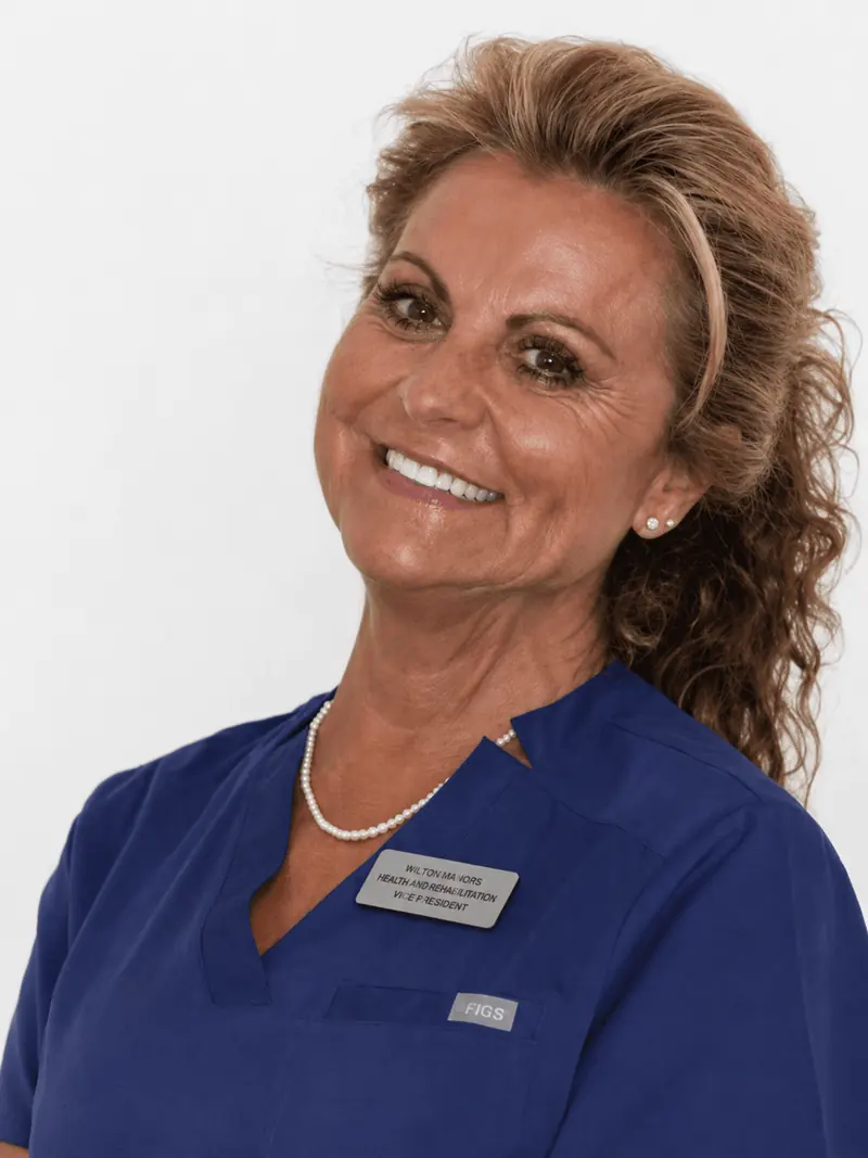 Retrato profesional de la Dra. Mayte Orts Rodríguez, fundadora y directora médica de Clínica Dental Arosa, con uniforme clínico azul