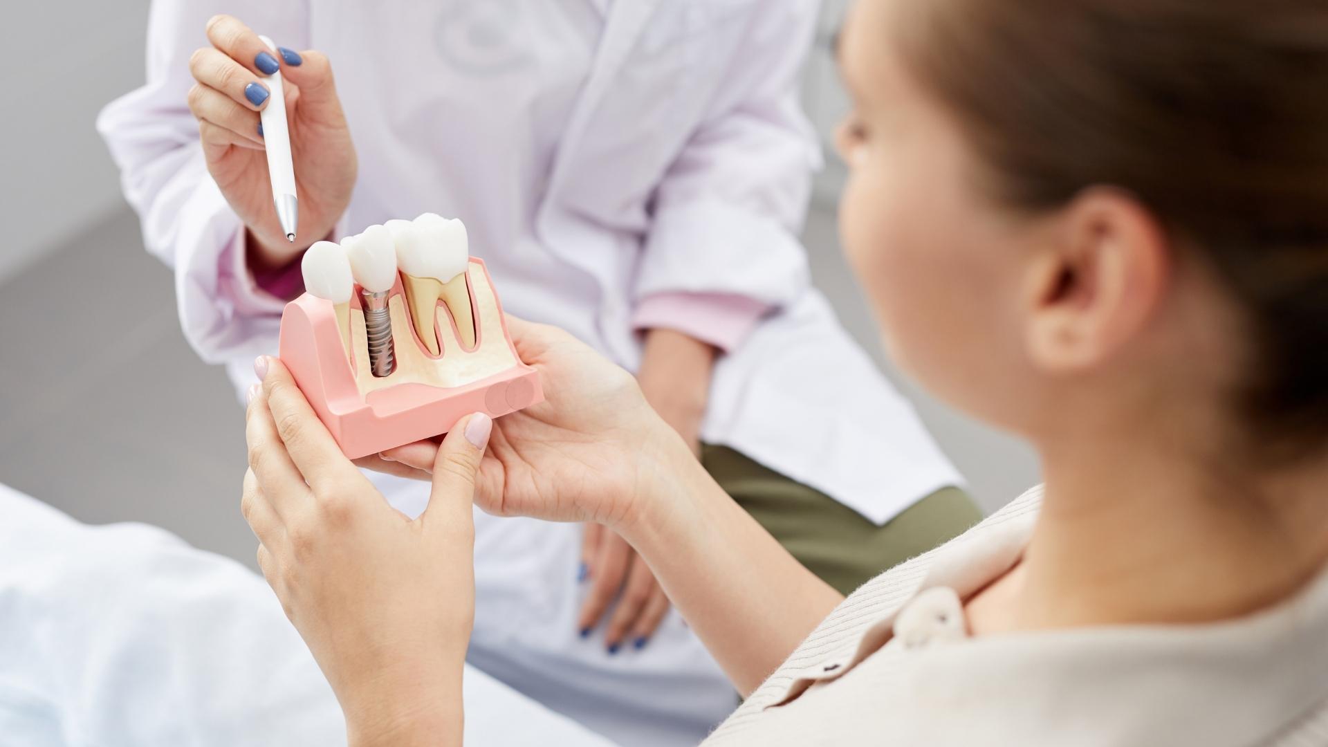 Doctora explicando con un modelo cómo se sujeta una prótesis dental, en Peñagrande